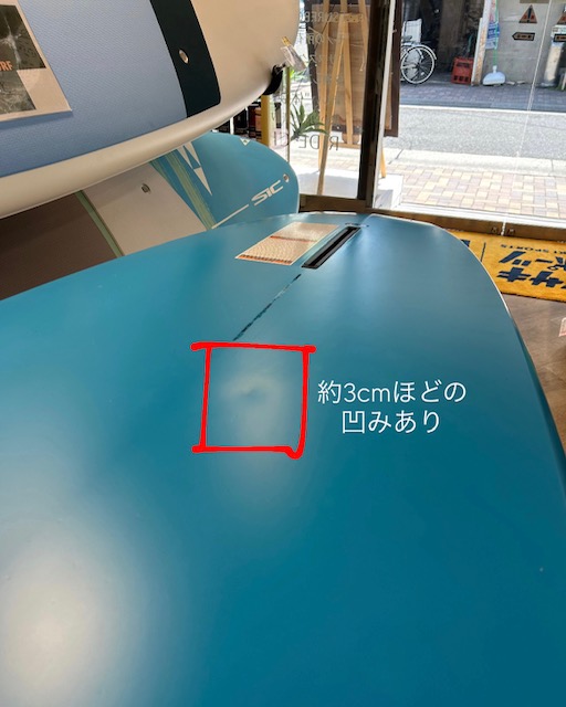 Close-up of a blue machine surface with a small dent about 3 cm, outlined in red; there is Japanese text noting the dent on the panel.