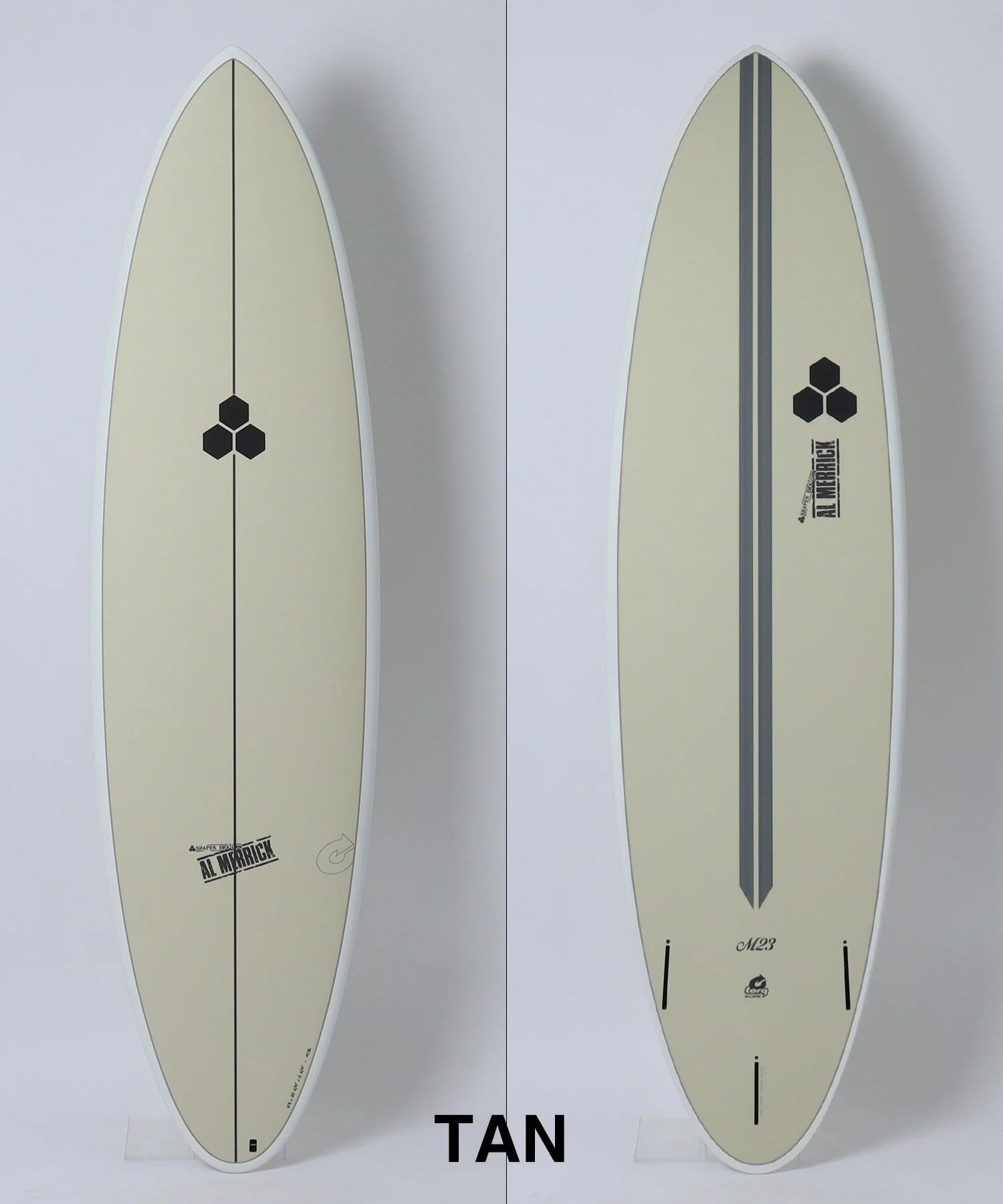 image - SHOP NEWS | ムラサキスポーツオンラインストア 通販 Two views of a tan surfboard: left side shows the front with a single black center stringer and a small hexagon emblem; right side shows the back with a double center groove and the hexagon emblem near the tail.